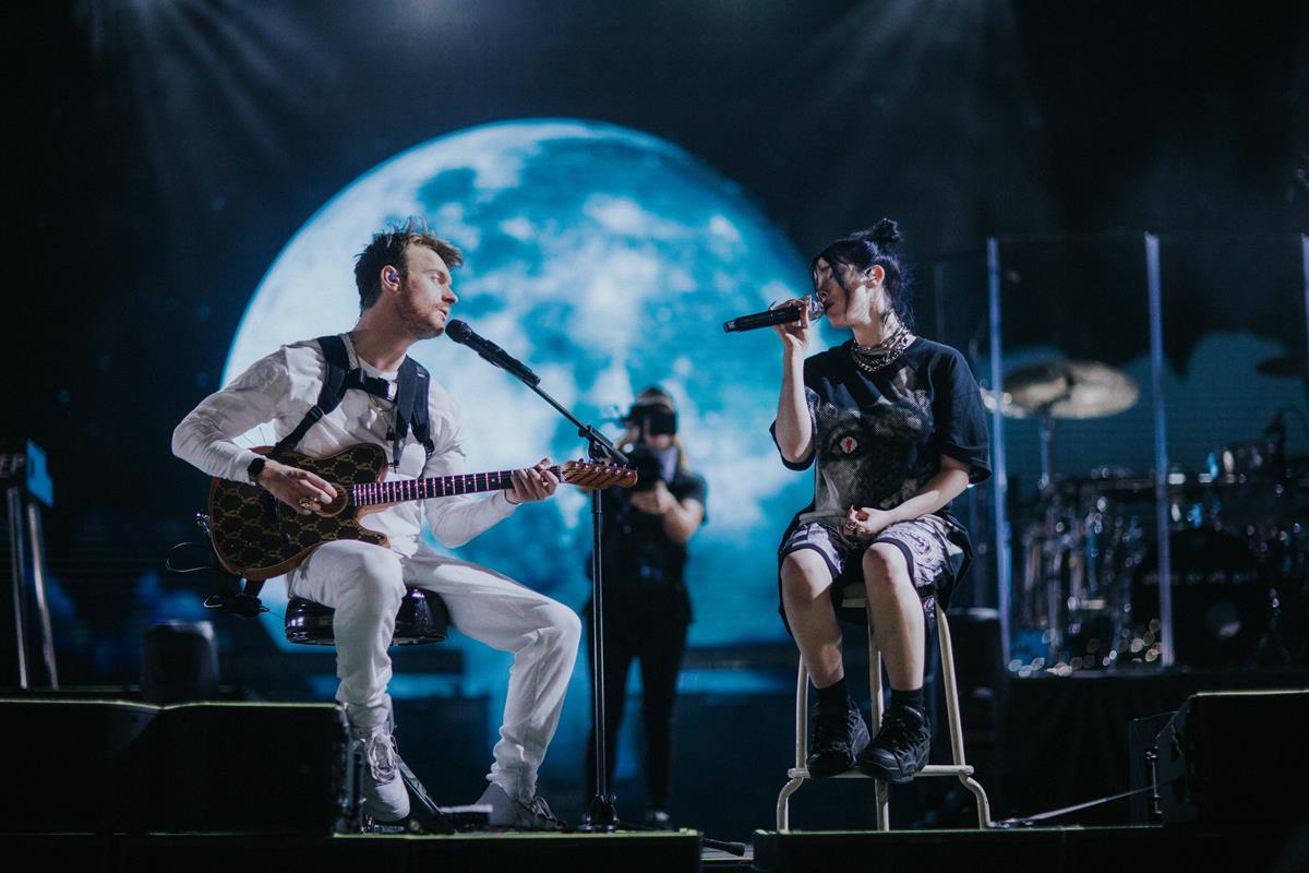 Billie Eilish and Finneas O’Connell on stage in “Billie Eilish: The World’s A Little Blurry.” Cr: Apple TV+